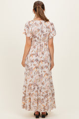 woman wearing a floral print maternity maxi dress with short flutter sleeves and a cinched waist from the back