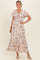woman wearing a white floral maxi dress with short sleeves and a tie-front detail