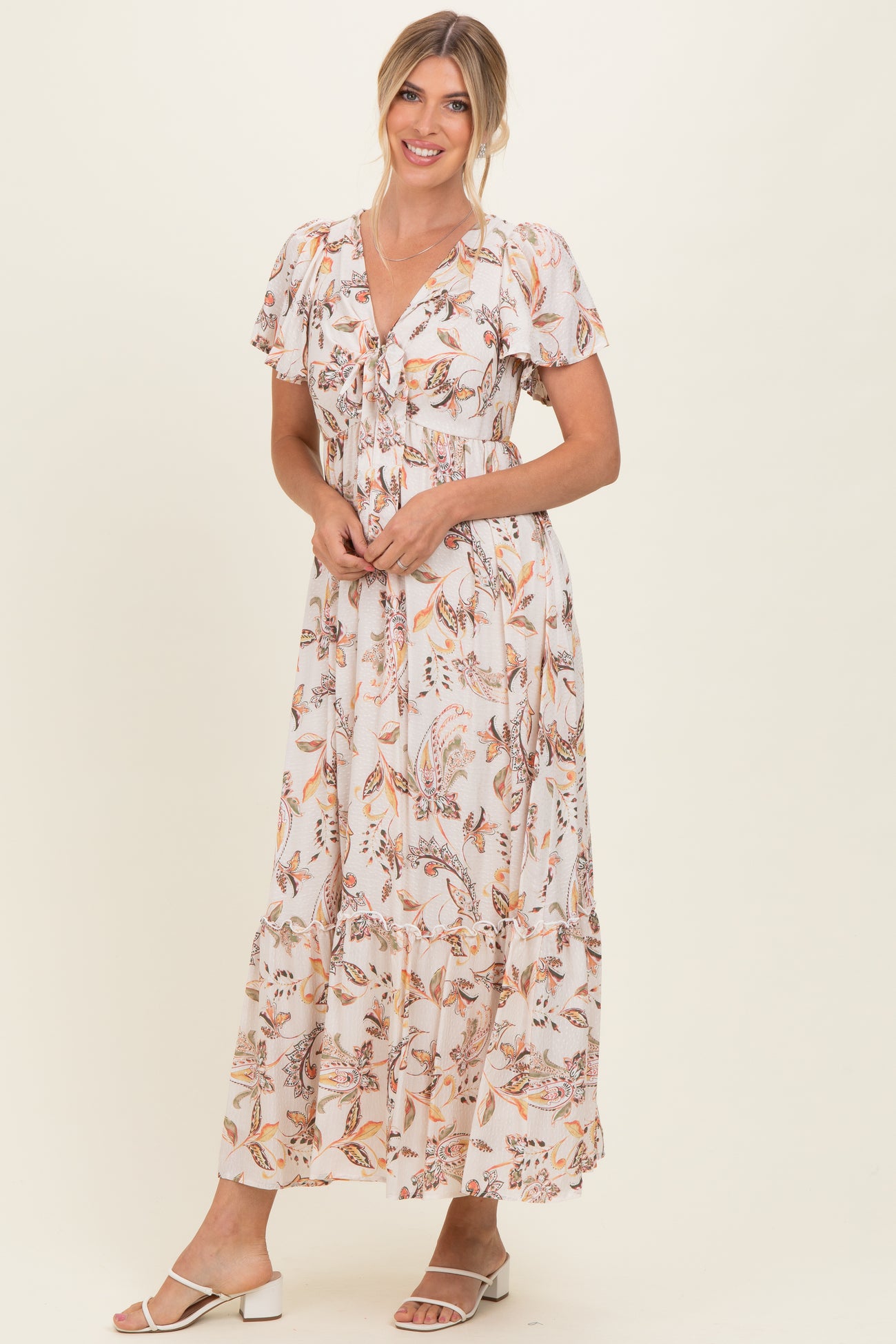woman wearing a floral maxi dress with short puff sleeves and a tied neckline