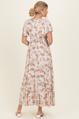 woman wearing a floral print maxi dress with flutter sleeves and a tiered skirt, showing the back view