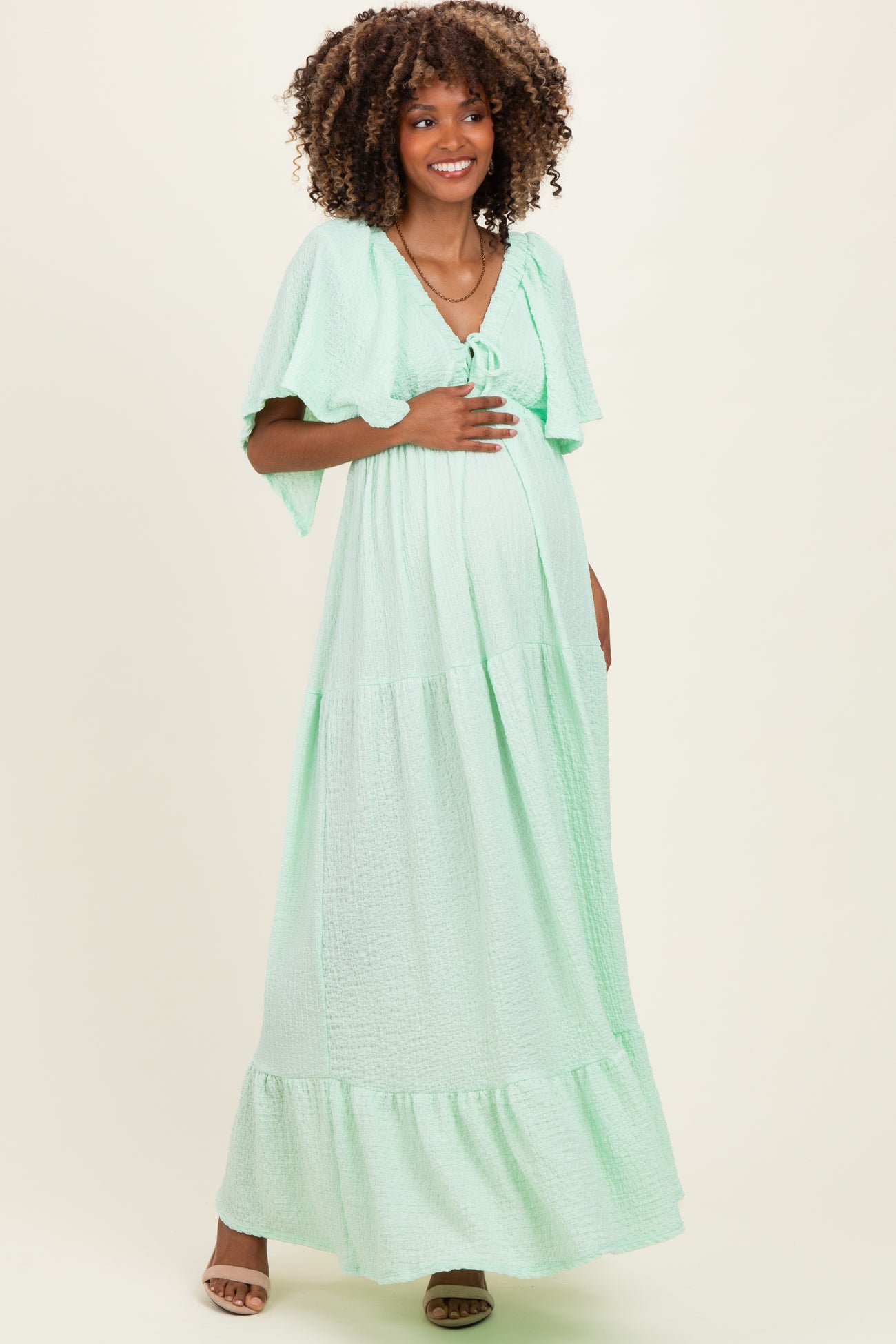 woman wearing a mint green maternity maxi dress with short flutter sleeves and a baby bump visible