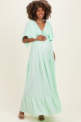 woman wearing a mint green maternity maxi dress with short flutter sleeves and a baby bump visible