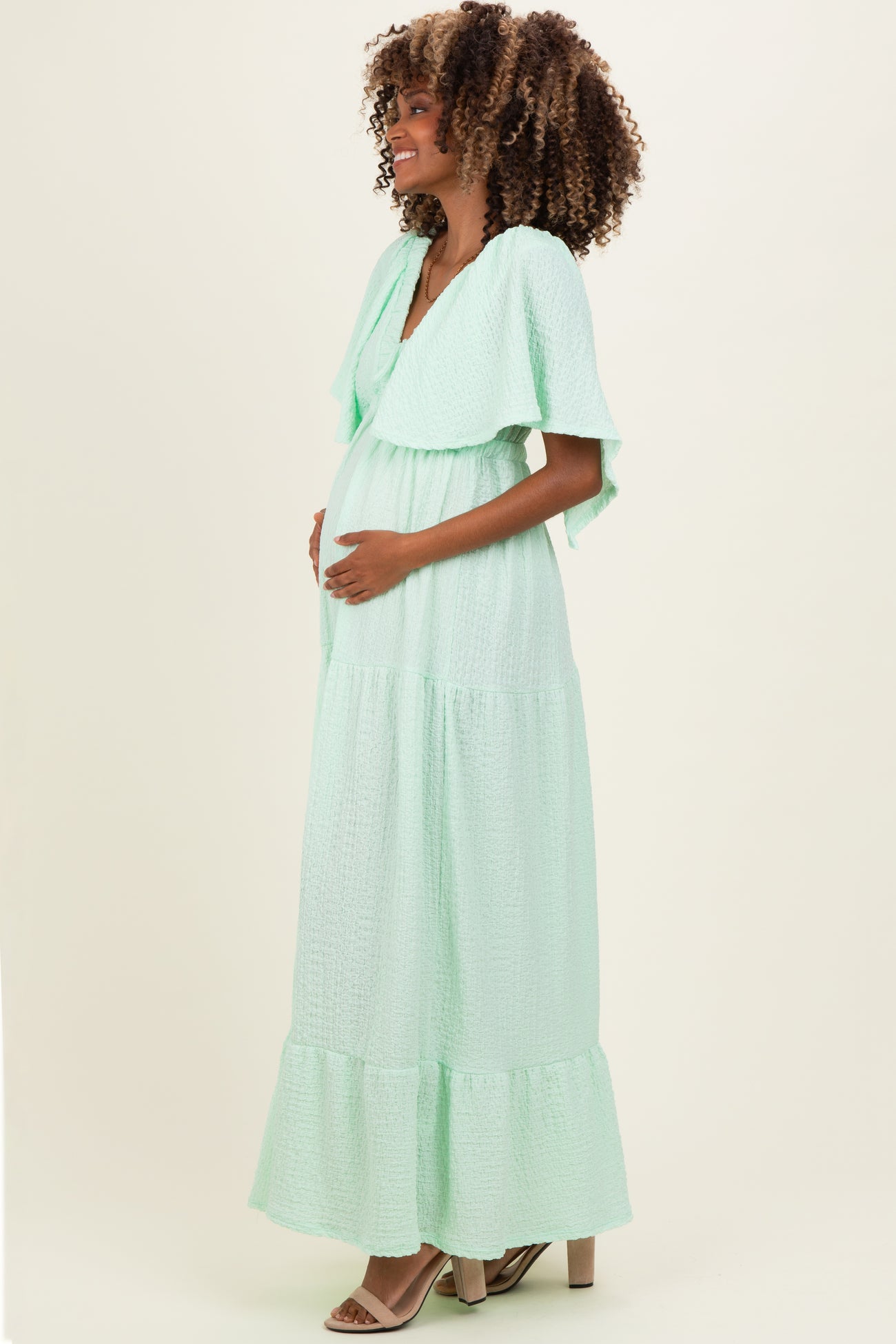 woman wearing a mint green maxi maternity dress with flutter sleeves and a visible baby bump