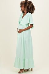 woman wearing a mint green maxi maternity dress with flutter sleeves and a visible baby bump