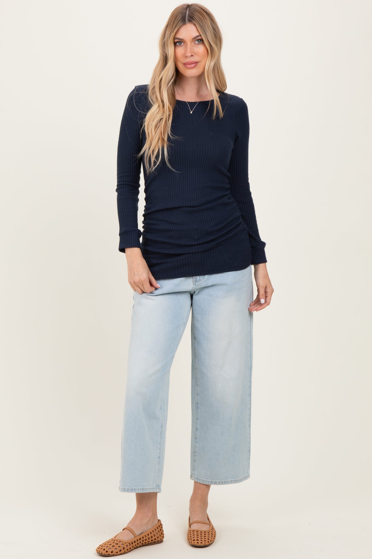 woman wearing a navy blue ribbed long sleeve top and light wash wide leg jeans with stylish brown flats