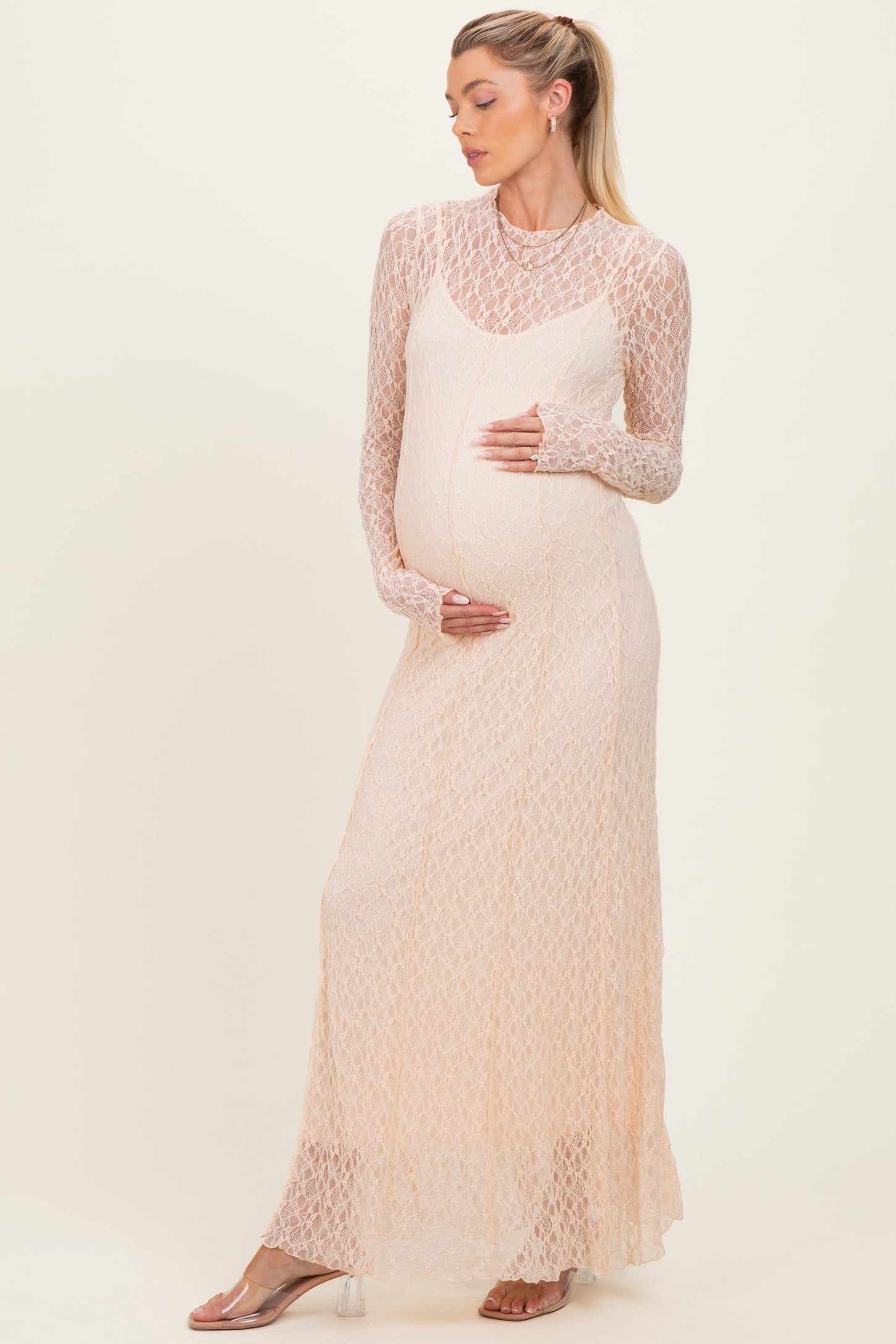 woman wearing a peach lace maternity dress with long sleeves and a visible baby bump