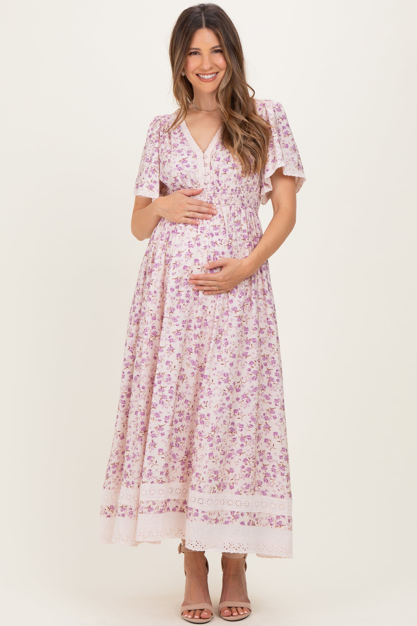 woman wearing a floral print maternity maxi dress with short sleeves and a v-neck, holding her baby bump