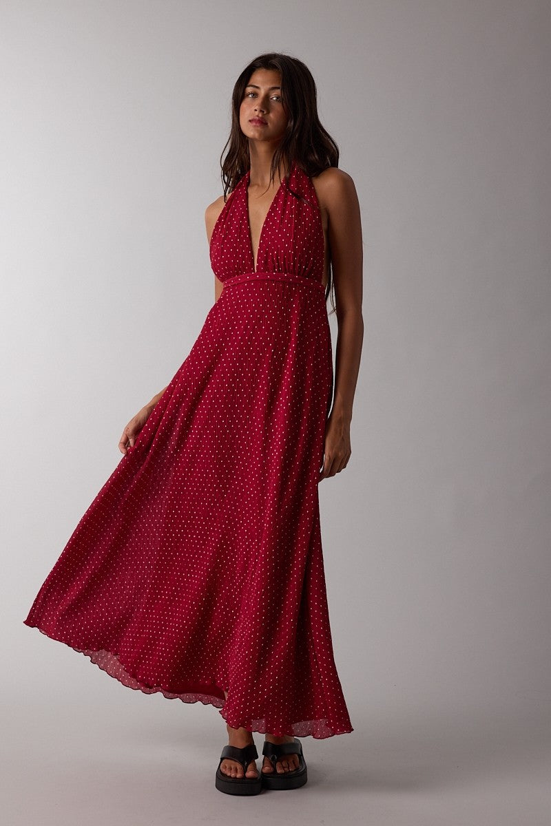 woman wearing a red halter neck maxi dress with white polka dots and a flowing skirt