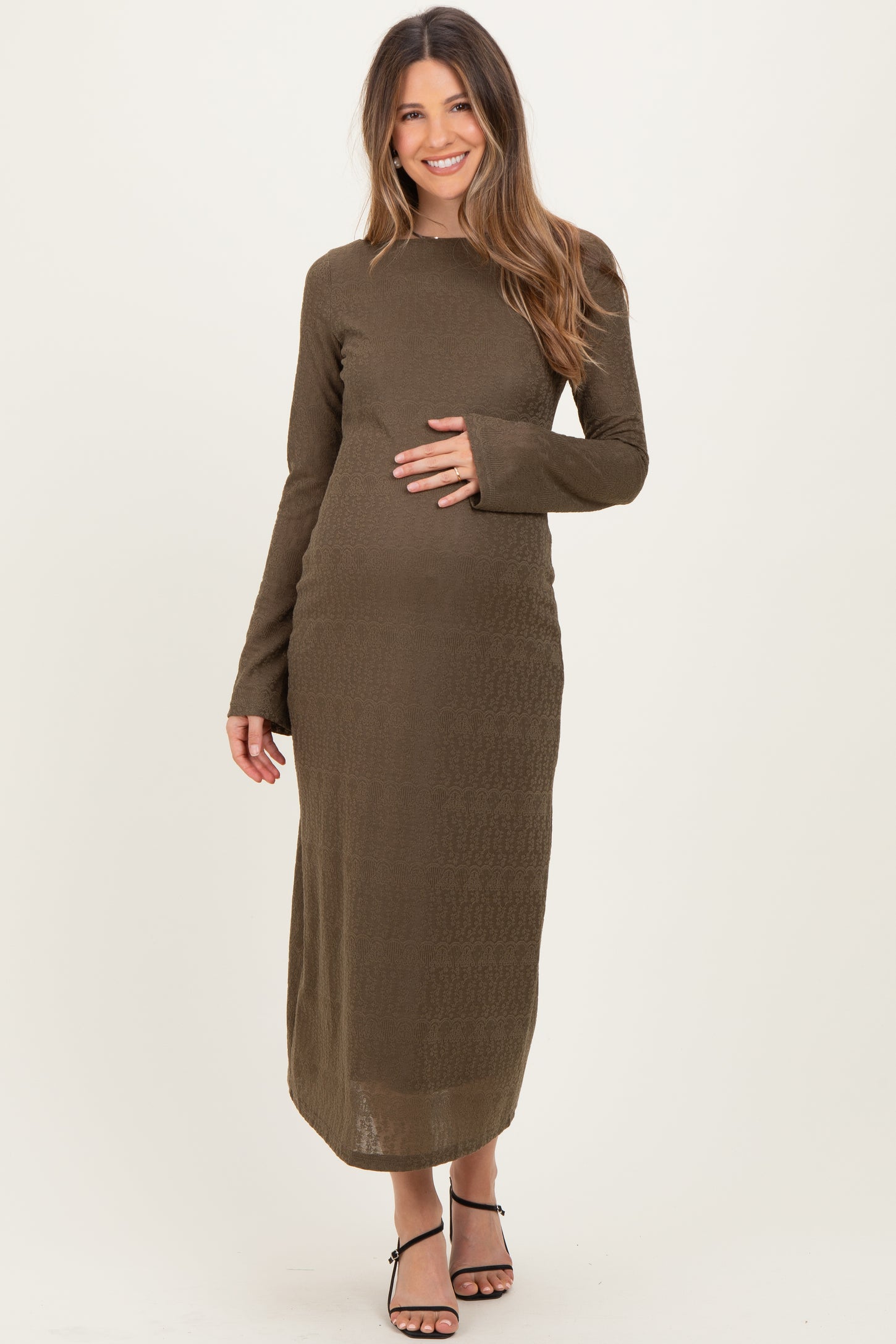 woman wearing a long sleeve olive green maternity dress, gently cradling her baby bump