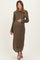 woman wearing a long sleeve olive green maternity dress, gently cradling her baby bump