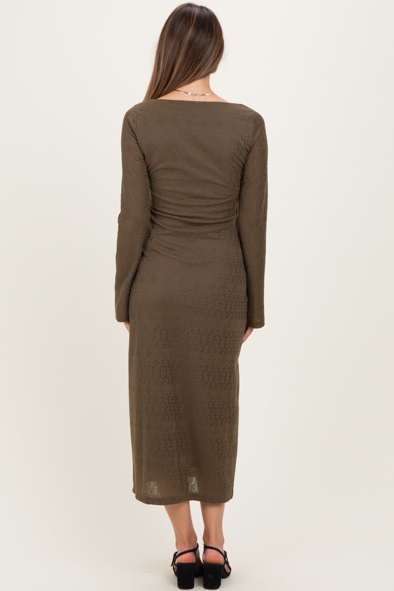 woman wearing a long olive green maternity dress with long sleeves and a fitted silhouette, showing a smooth back view
