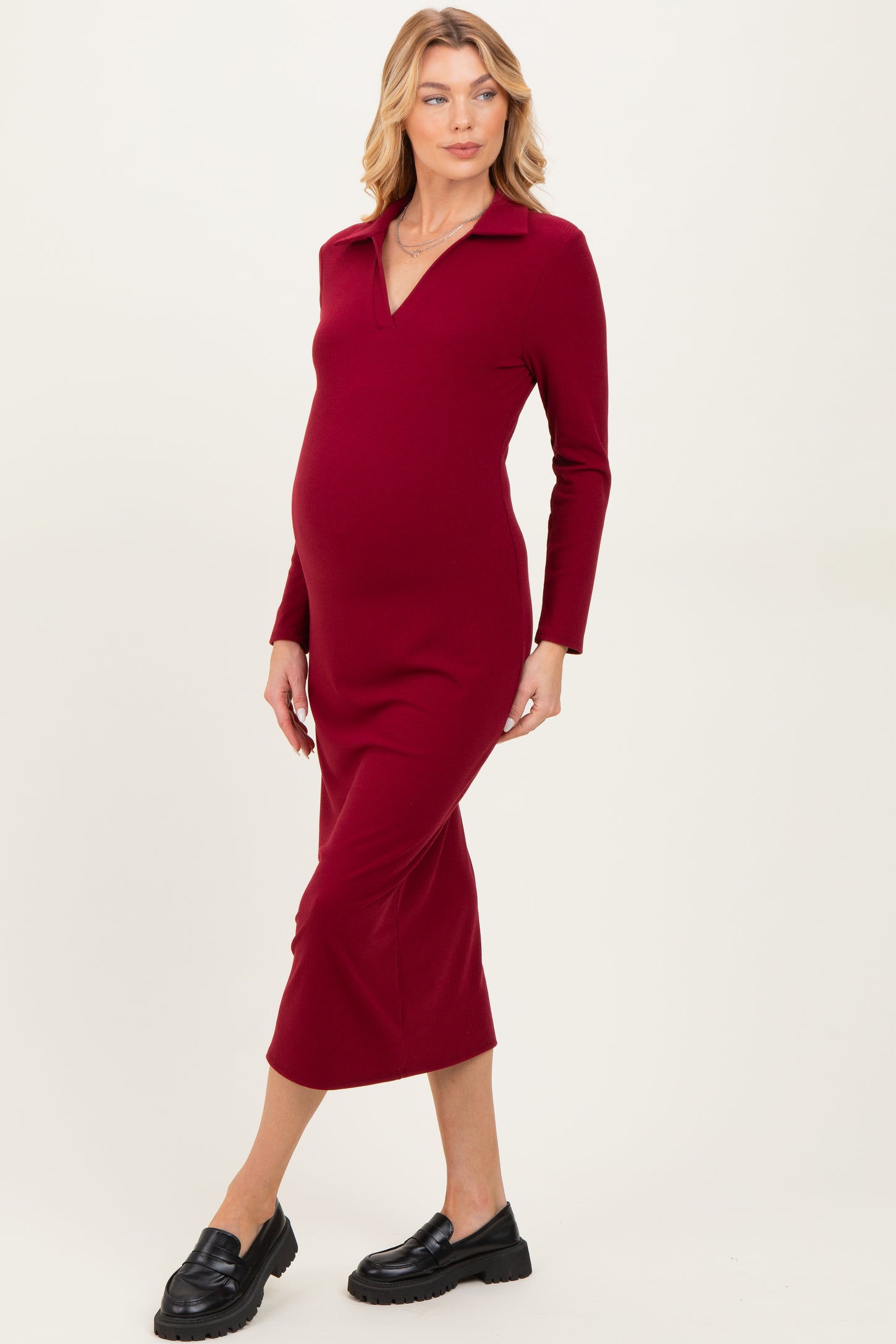 woman wearing a burgundy long sleeve maternity dress with a collared neckline and a visible baby bump