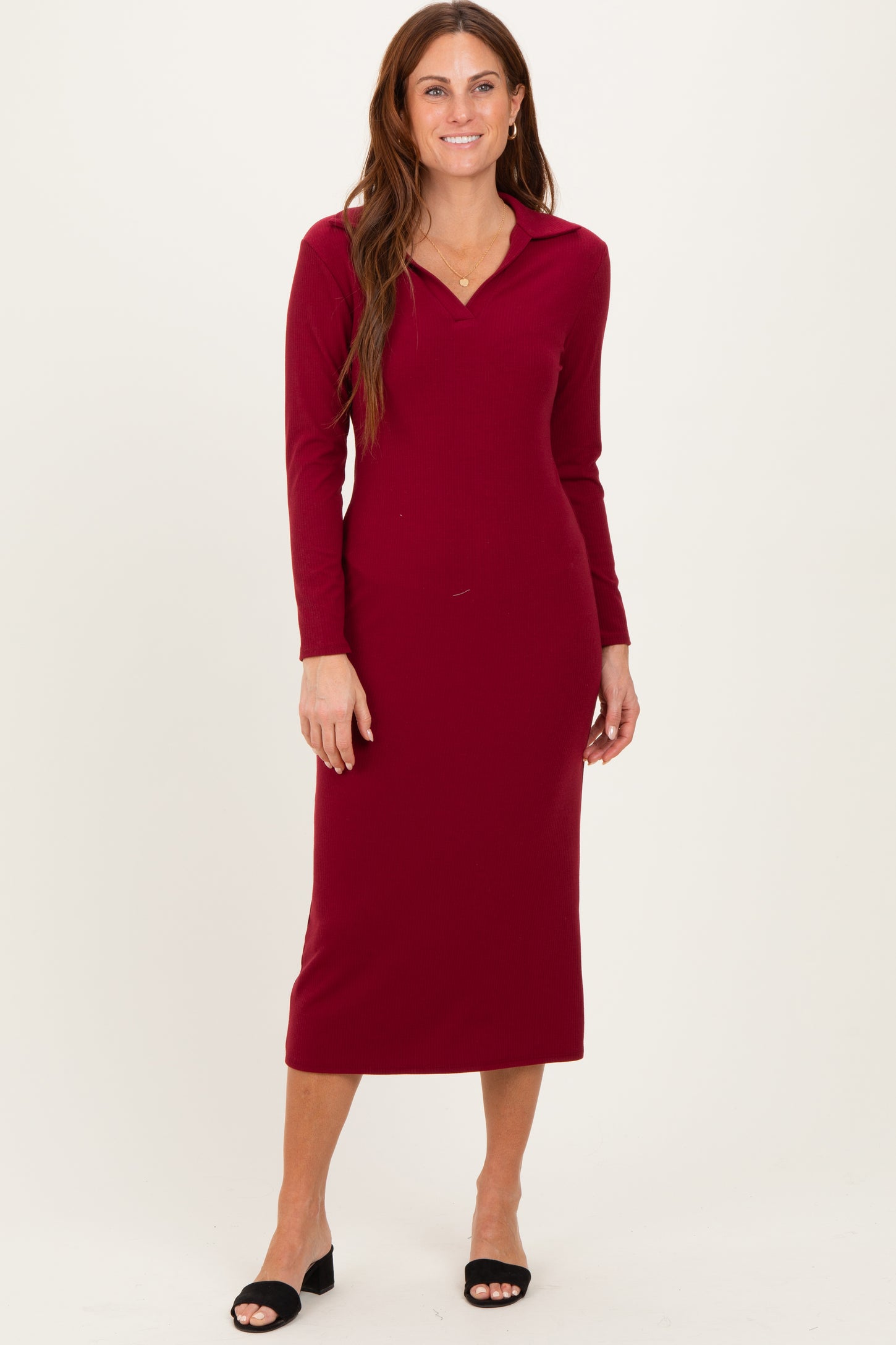woman wearing a burgundy long sleeve midi dress with a collar and fitted silhouette, standing with a smile