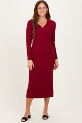 woman wearing a burgundy long sleeve midi dress with a collar and fitted silhouette, standing with a smile