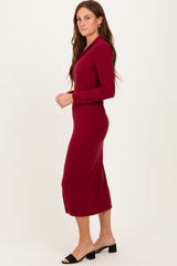 woman wearing a burgundy long sleeve fitted midi dress with a collar and side slit, standing in profile