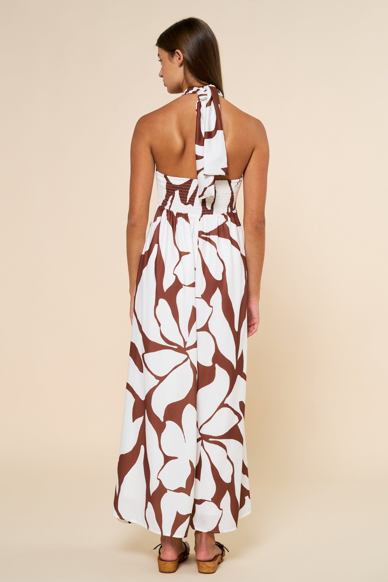 woman wearing a white and brown floral maxi dress with a halter neck and smocked back, showcasing a relaxed fit