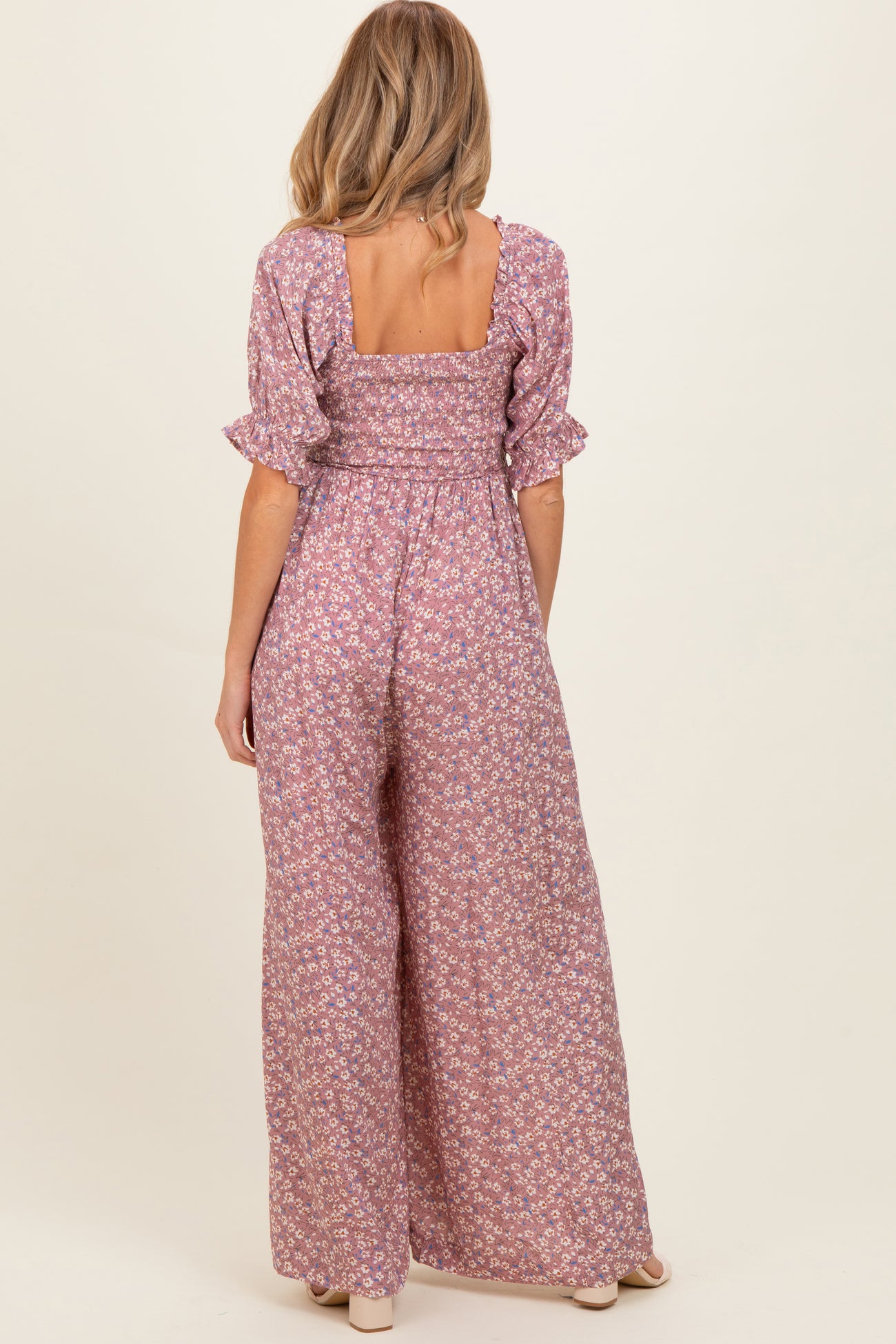 woman wearing a floral print pink maternity jumpsuit with short puff sleeves and a square back