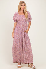 woman wearing a purple floral maxi dress with square neckline and puff sleeves, standing with hands in pockets