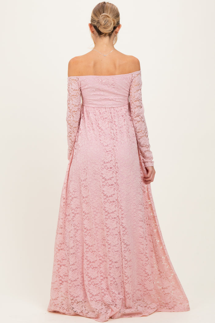 woman wearing a soft pink off-shoulder lace maternity gown with long sleeves and a flowing skirt