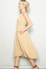 woman wearing a yellow gingham sleeveless midi dress with side pockets and a fitted bodice