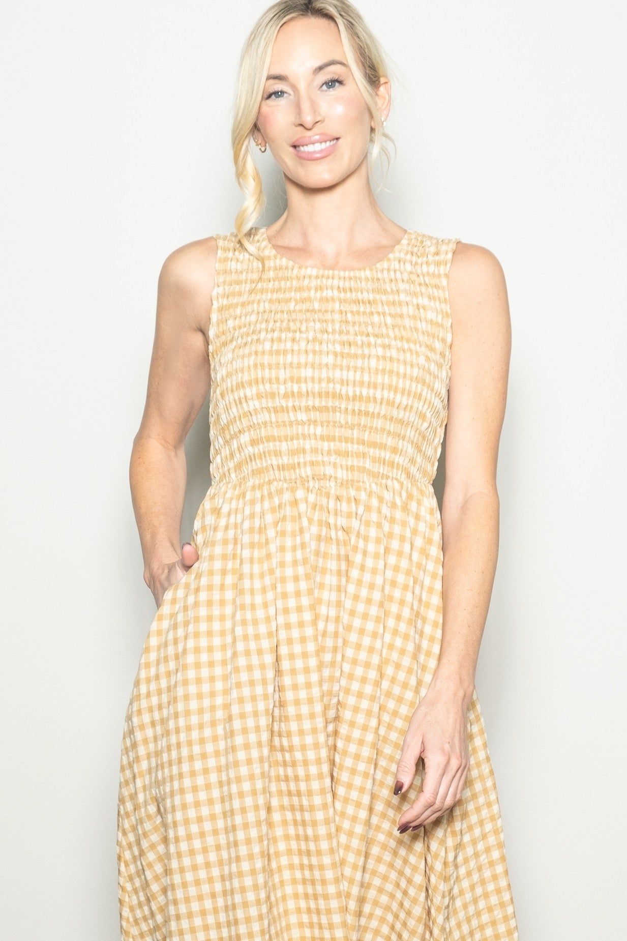 woman wearing a yellow gingham smocked sundress with a scoop neckline and side pockets