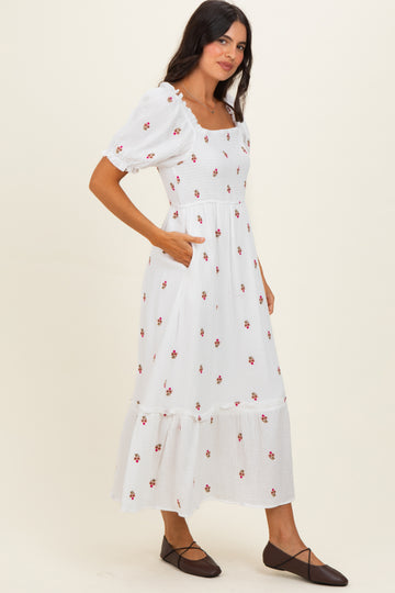 woman wearing a white floral midi dress with puff sleeves and pockets, standing on a neutral background