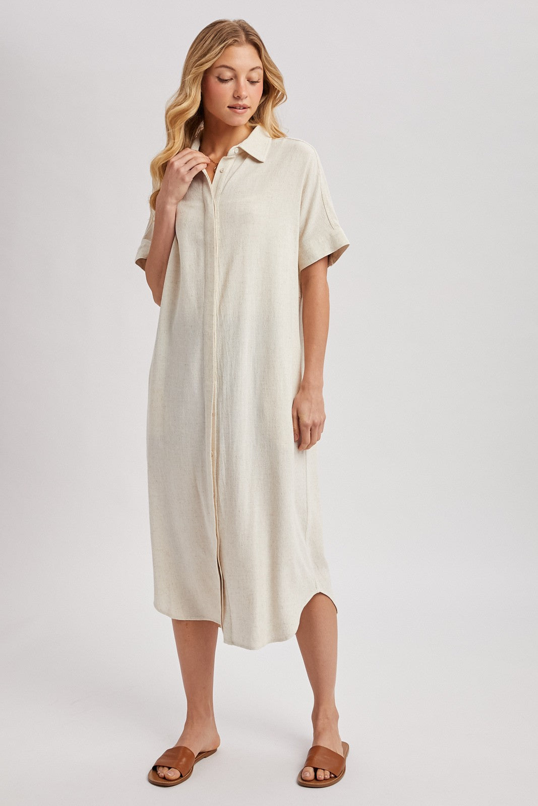 woman wearing a beige short sleeve button-up midi dress and brown sandals