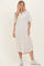 woman wearing a light beige linen button-up midi dress with short sleeves and white sneakers