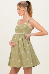 woman wearing a green floral maternity dress, showcasing her baby bump with a fitted bodice and flared skirt