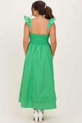 woman wearing a vibrant green maternity maxi dress with ruffle straps and smocked back, showcasing a baby bump