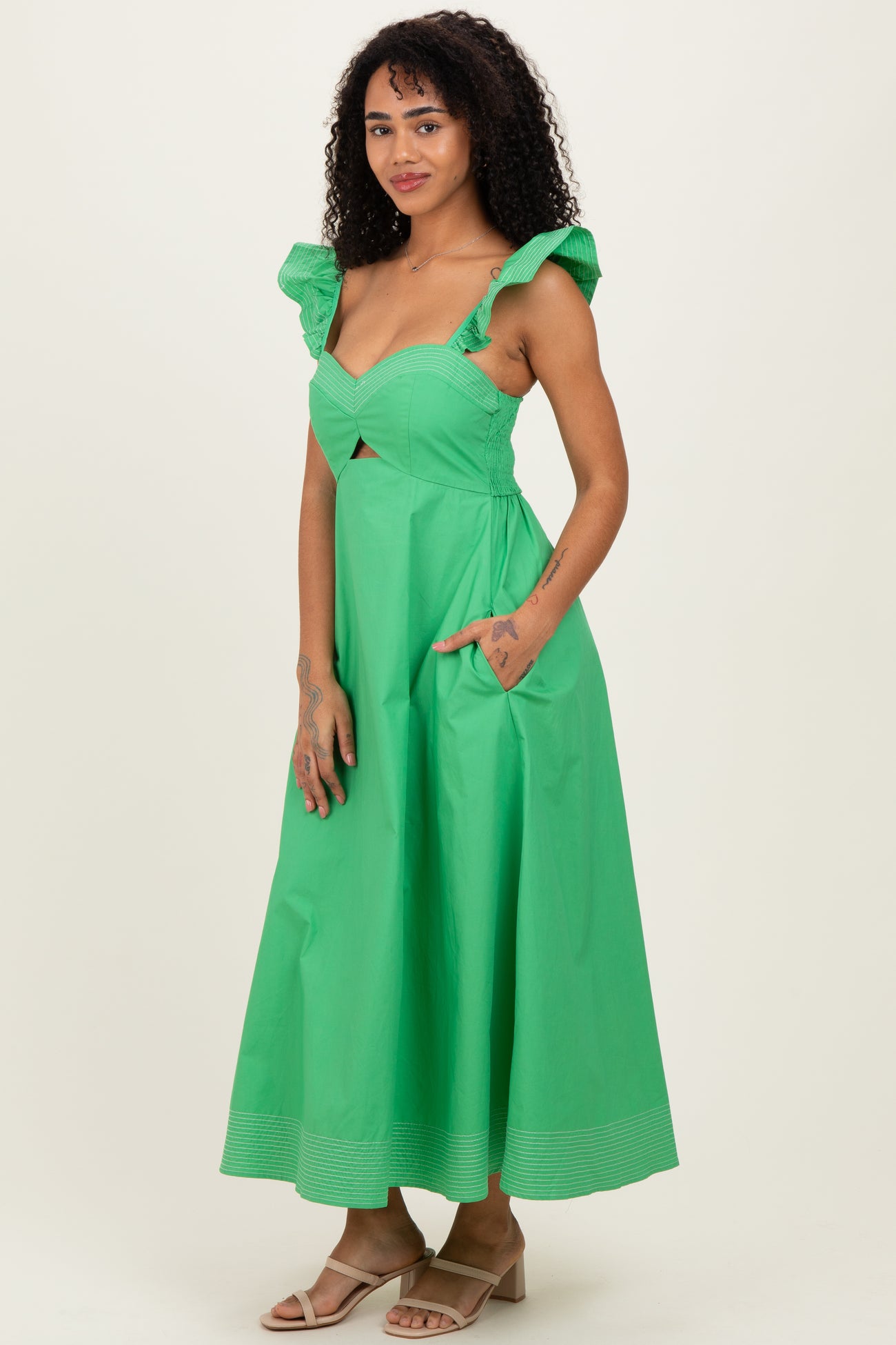 woman wearing a green midi dress with ruffled straps and side pockets