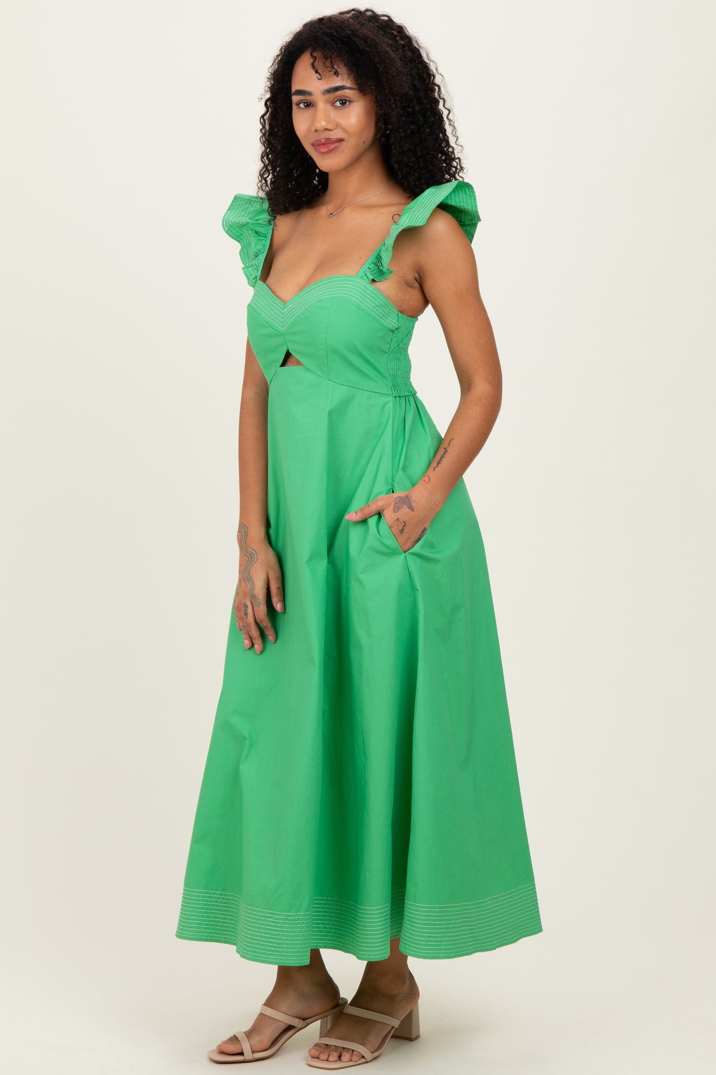 woman wearing a green midi dress with ruffled straps and side pockets