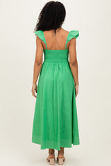 woman wearing a green backless maxi dress with ruffled straps and a smocked bodice