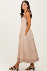 woman wearing a light beige maxi dress with a structured collar and side pockets, standing sideways