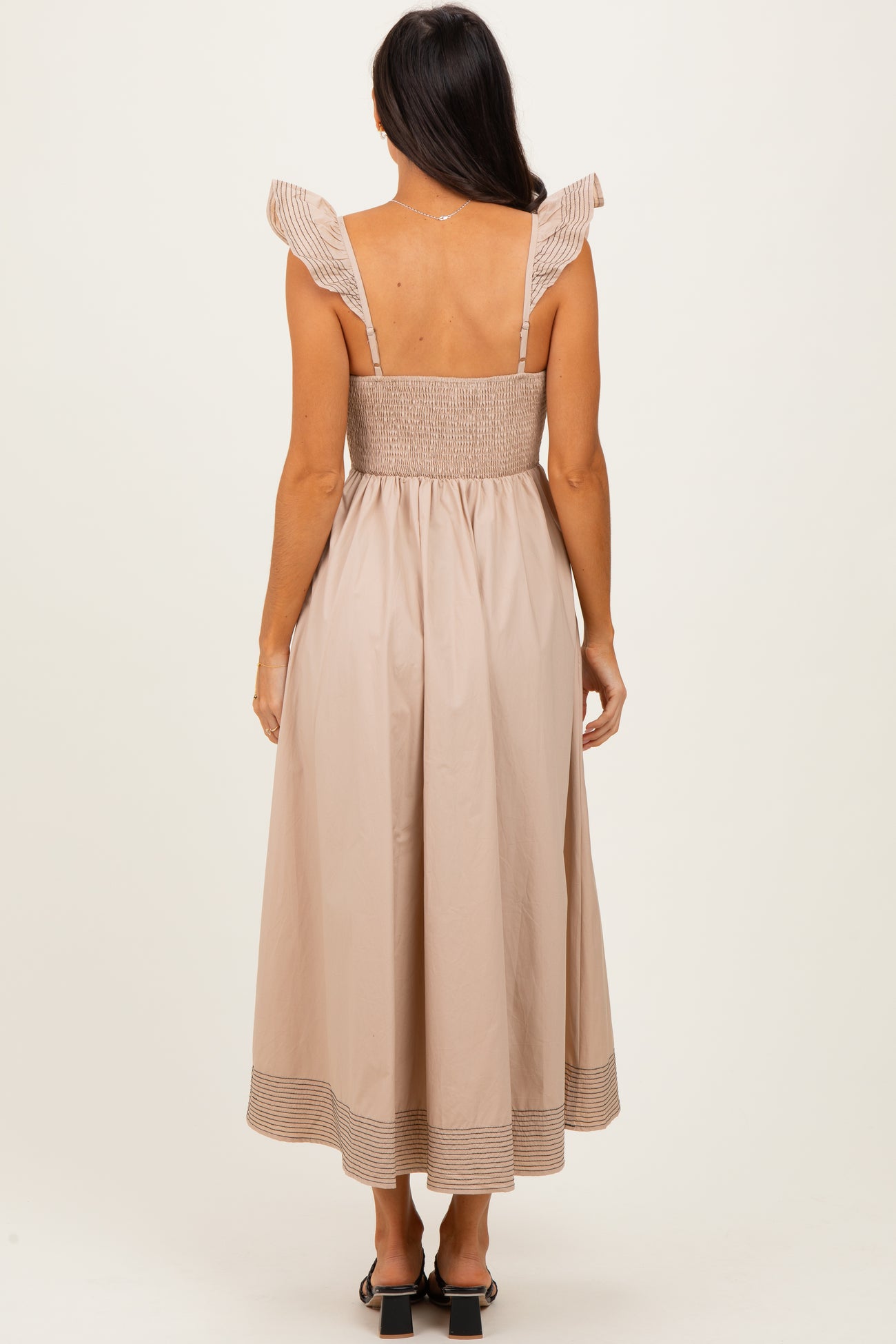 woman wearing a light beige mid-length dress with ruffled straps and a smocked bodice