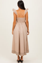 woman wearing a light beige mid-length dress with ruffled straps and a smocked bodice