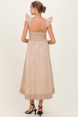 woman wearing a beige maternity dress with ruffle shoulder straps and a smocked bodice, showing a flowing skirt