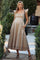 woman wearing a beige maternity dress with ruffled sleeves and a baby bump, standing in a garden setting