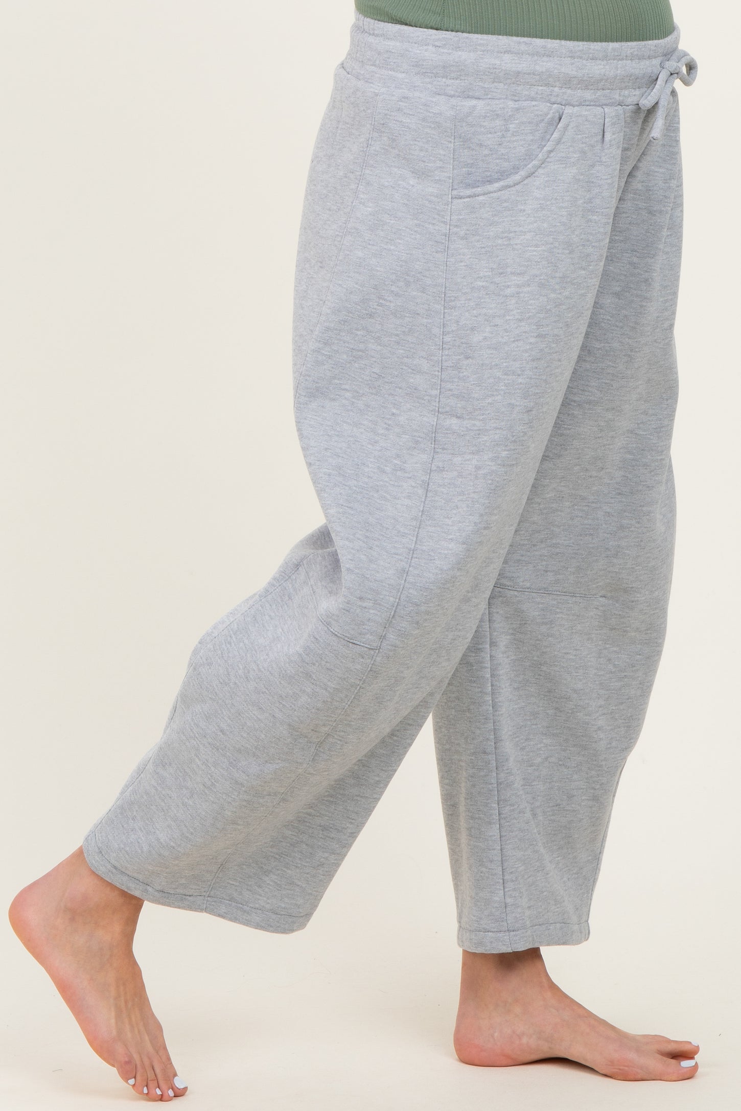 maternity wear grey sweatpants with side pockets and a drawstring waistband, model showing one leg while barefoot