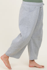maternity wear grey sweatpants with side pockets and a drawstring waistband, model showing one leg while barefoot