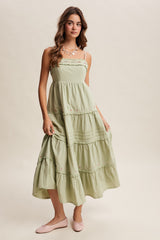woman wearing a light green maxi dress with floral embroidery and spaghetti straps, paired with pink ballet flats