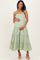woman wearing a light green tiered maternity dress with floral details and a baby bump visible