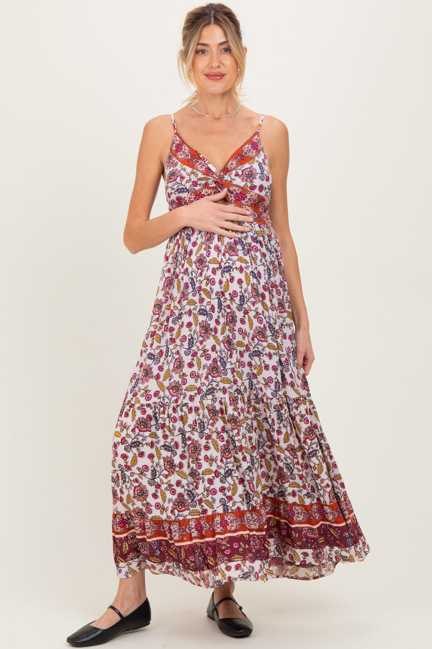 woman wearing a floral maxi maternity dress with adjustable straps and a twist front, featuring a visible baby bump