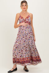 woman wearing a floral maxi maternity dress with adjustable straps and a twist front, featuring a visible baby bump