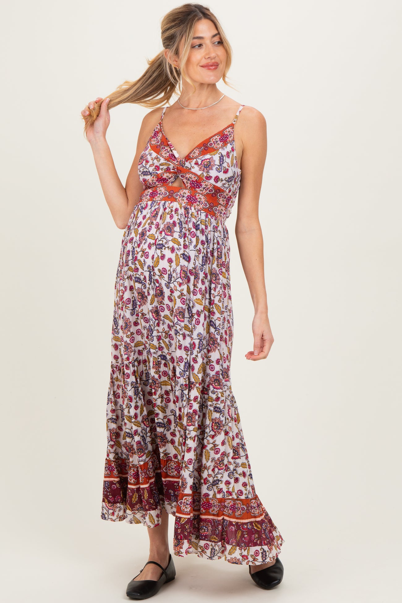 woman wearing a floral maternity maxi dress with a twisted front design and a visible baby bump