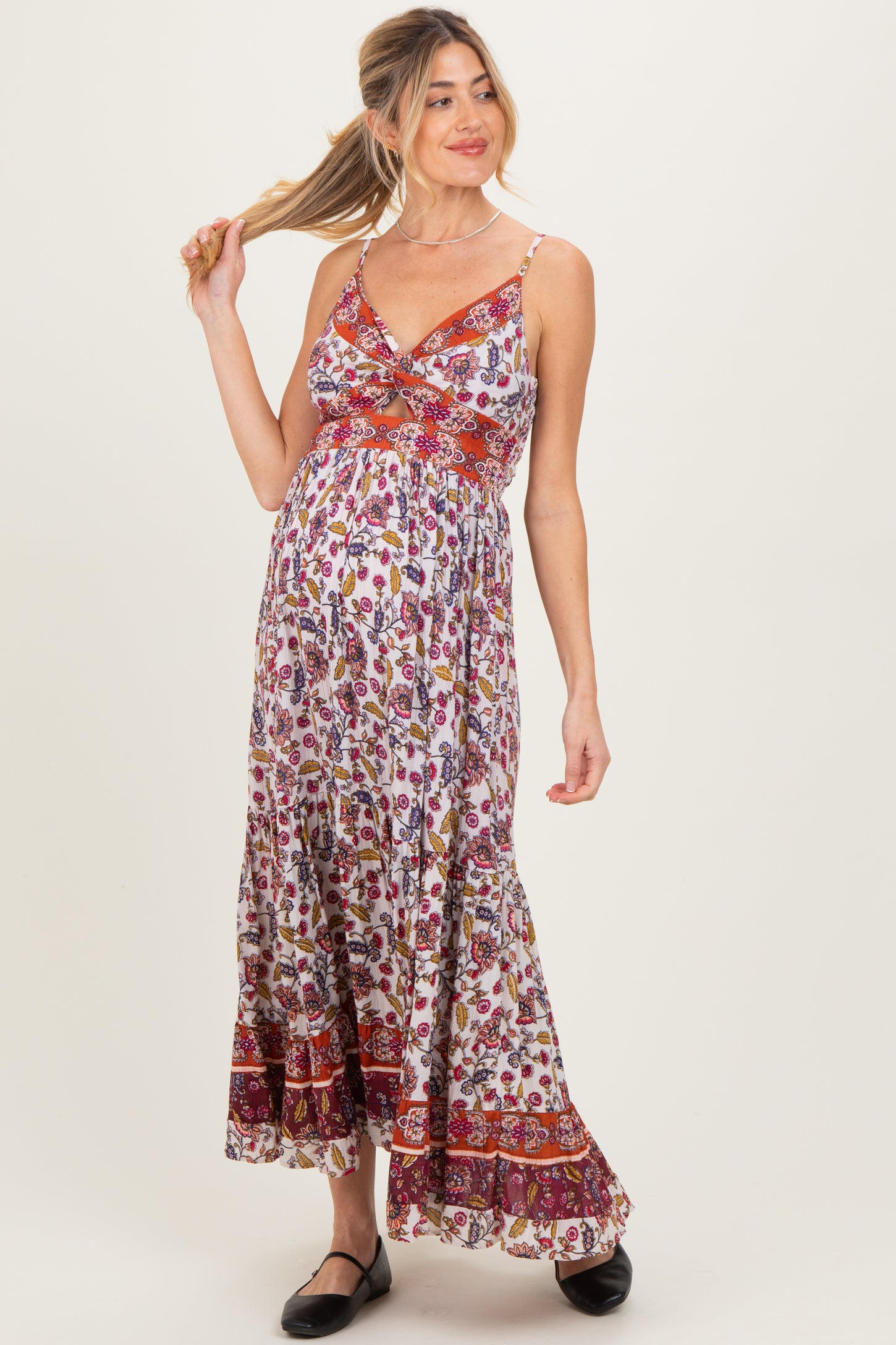 woman wearing a floral maternity maxi dress with a twisted front design and a visible baby bump