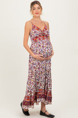 woman wearing a multi-colored floral maternity maxi dress and holding her baby bump