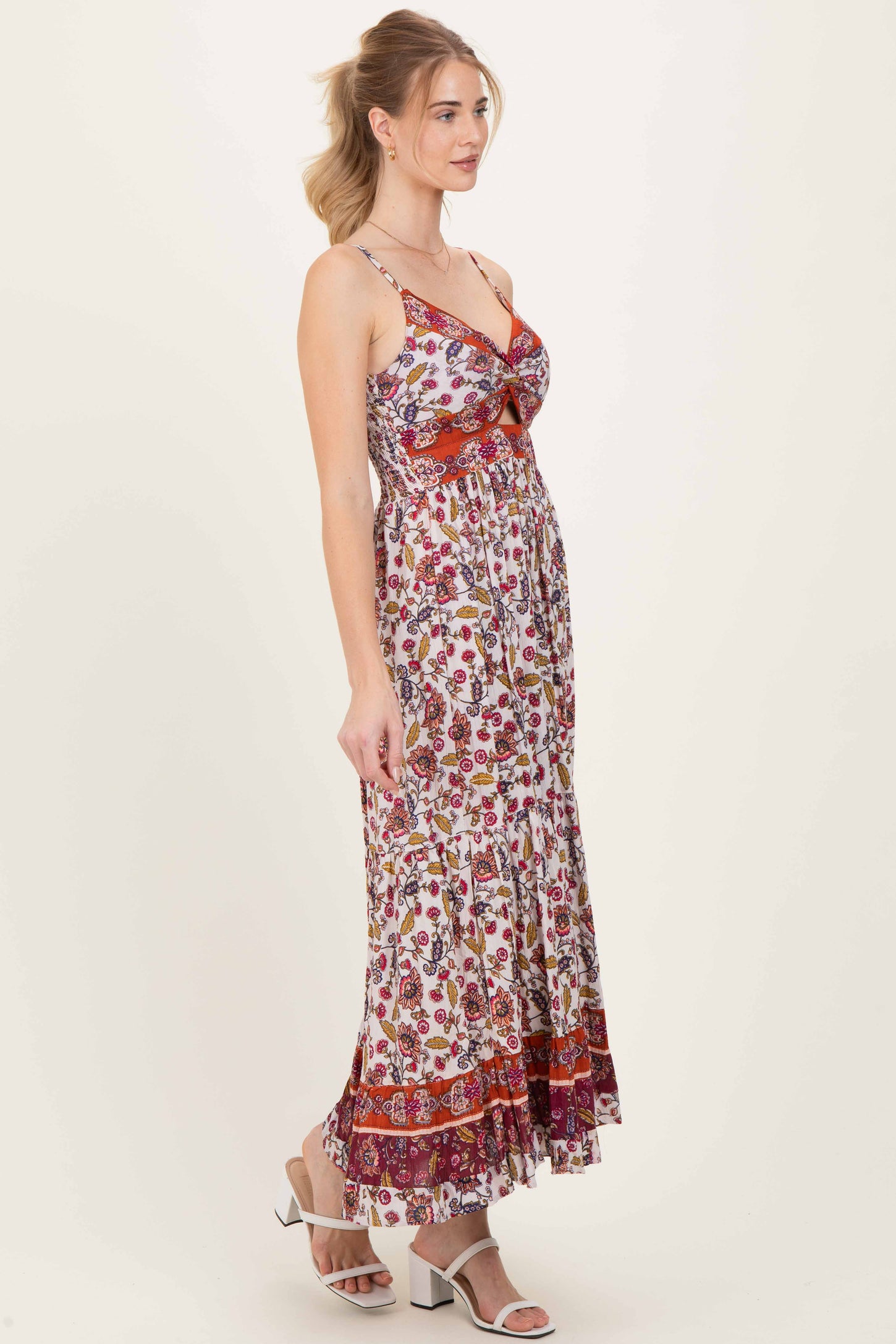 woman wearing a floral maxi dress with spaghetti straps and a red trim, posing sideways