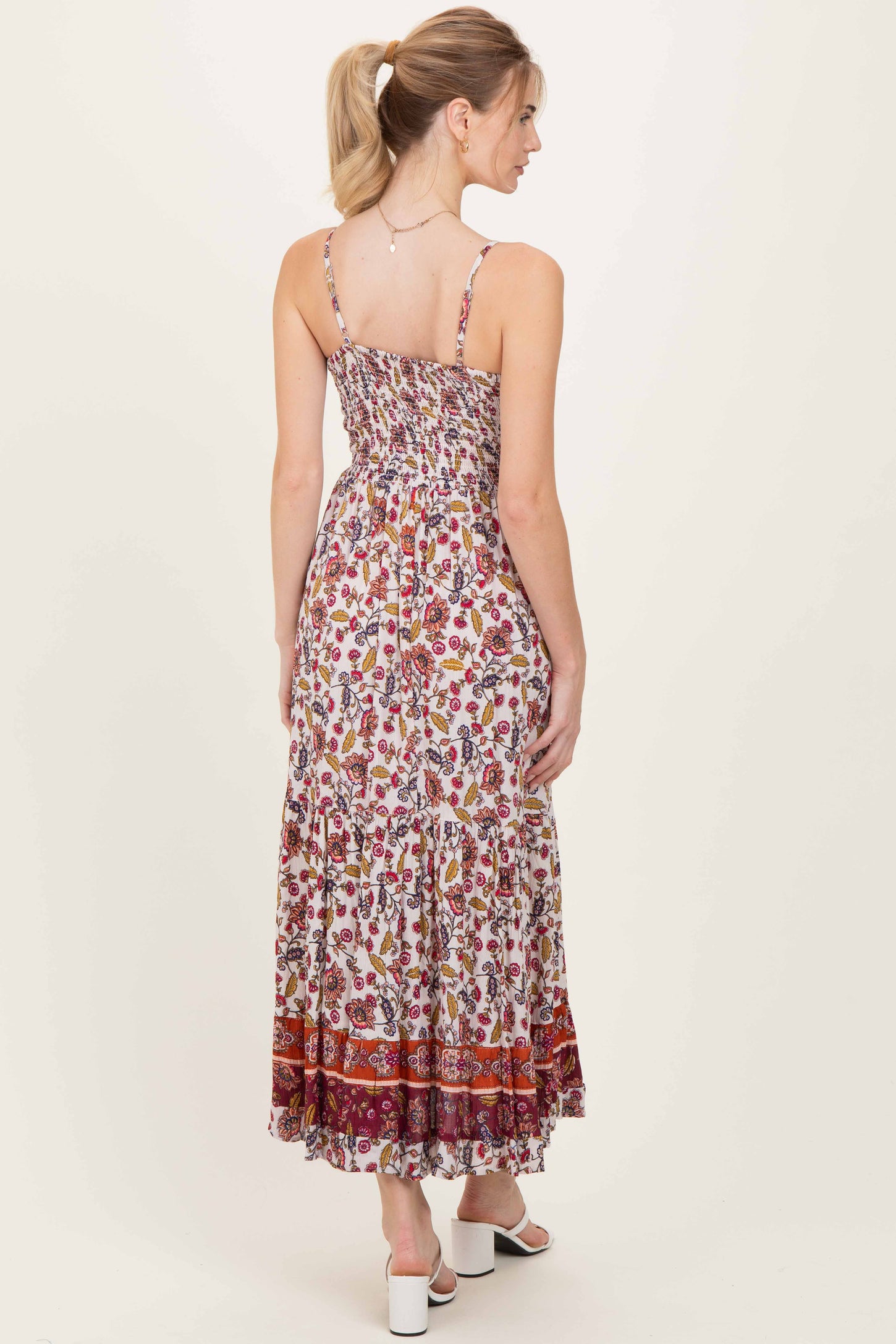 woman wearing a floral print maxi dress with smocked back and adjustable straps, viewed from the back