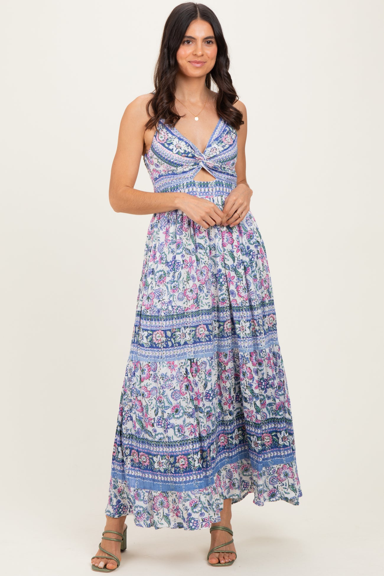 woman wearing a floral maxi dress with a knotted front and spaghetti straps, standing in a relaxed pose